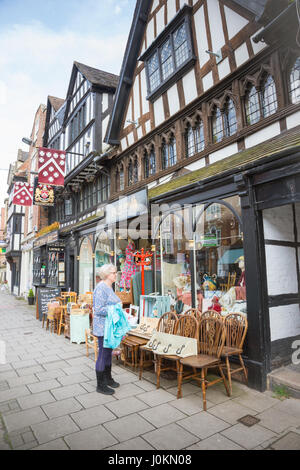 Donna in piedi al di fuori di un negozio nel centro di Tewkesbury, GLOUCESTERSHIRE REGNO UNITO mostra in legno tradizionali edifici incorniciate Foto Stock