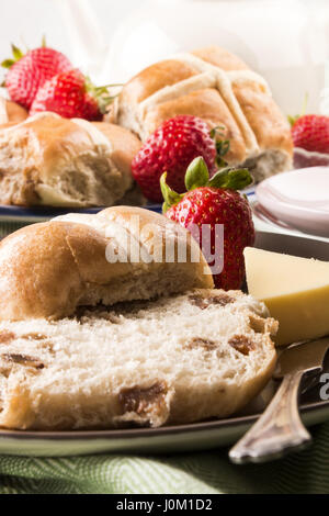 Hot cross panini e fragole dolci e burro su una piastra Foto Stock