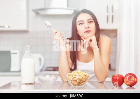 Una giovane donna si prepara un basso contenuto calorico prima colazione su una prescrizione mentre guardando il suo computer portatile. La dieta, mele, muesli, fiocchi di mais - il concetto di hea Foto Stock