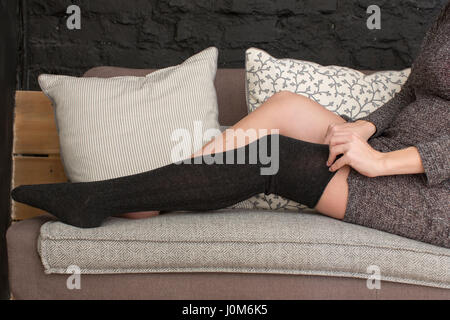 Femmina mettendo su calze nere Foto Stock