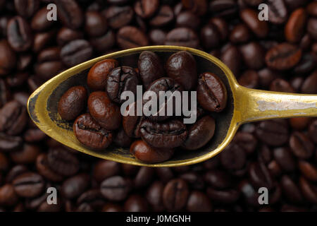 Età cucchiaio riempito con chicchi di caffè (caffè Robusta). Close-up, vista dall'alto. Foto Stock