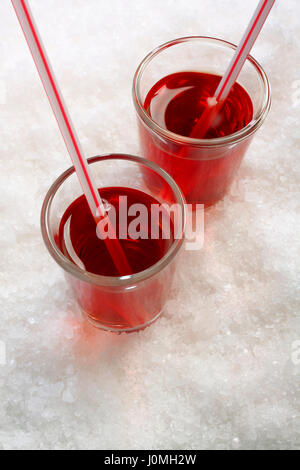 Bevande di colore rosso con un bere cannucce su sfondo di ghiaccio sminuzzato Foto Stock