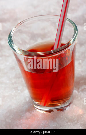 Red drink in vetro su sfondo di ghiaccio sminuzzato. Telaio obliquo. Foto Stock