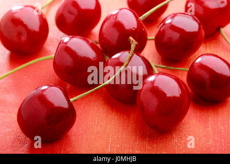 Ciliegie dolci sul dipinto di rosso sfondo tessili Foto Stock