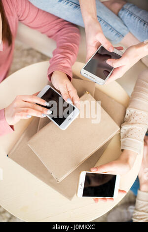 Vista in pianta parziale di tre giovani donne utilizzando gli smartphone con schermi vuoti Foto Stock