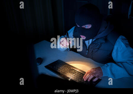 Hacker ladro digitando sulla tastiera in ufficio Foto Stock