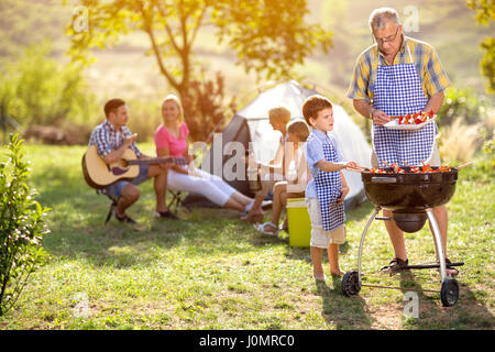 Nonno e nipote a barbecue grill con la famiglia a cena Foto Stock