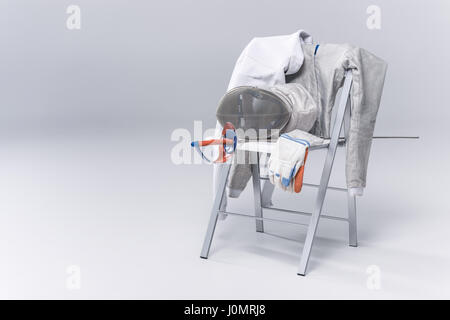 Professional Fencing Equipment sulla sedia su sfondo grigio Foto Stock