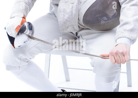 Ritagliato colpo di volante professionale tenendo il casco e rapier mentre è seduto su una sedia Foto Stock