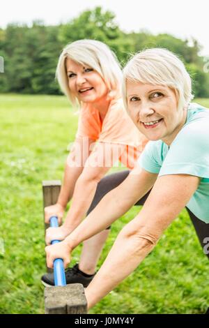 Due donne sorridente verso la telecamera tenendo ringhiera. Foto Stock