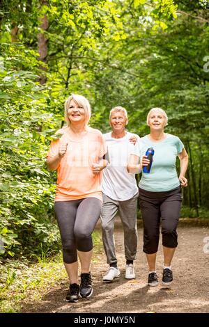 Tre persone in esecuzione sulla via di boschi. Foto Stock