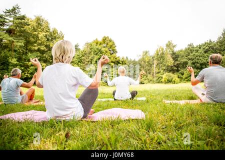 Quattro persone fare yoga in campo. Foto Stock