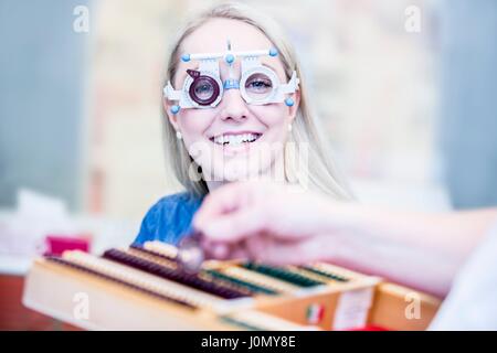 Ritratto di Allegro giovane donna indossa il telaio di prova in all'ottico optometrista del negozio, close-up. Foto Stock