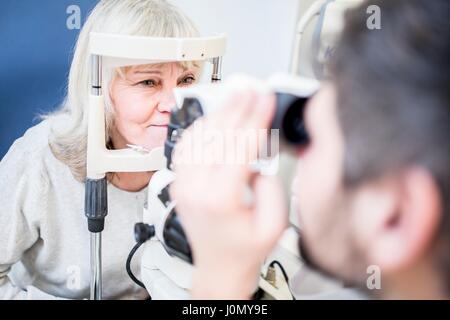 All'ottico optometrista esaminando occhi di donna con lampada a fessura. Foto Stock