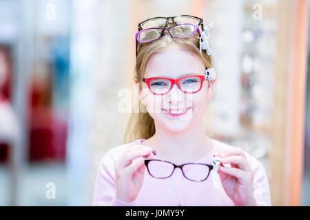 Ritratto di ragazza cercando bicchieri in all'ottico optometrista del negozio. Foto Stock