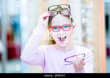 Ritratto di ragazza cercando bicchieri in all'ottico optometrista del negozio. Foto Stock