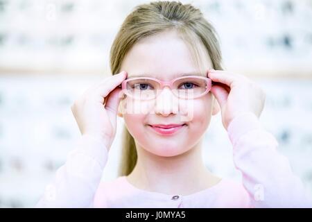 Ritratto di ragazza cercando bicchieri in all'ottico optometrista del negozio. Foto Stock