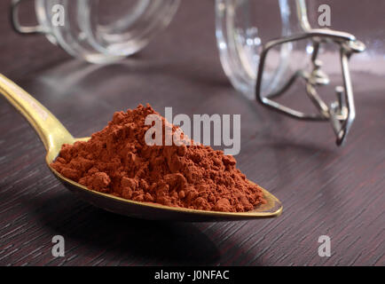Ottone antico cucchiaio colmo di cacao in polvere sul bordo scuro Foto Stock