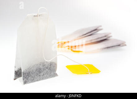 Bustine di tè con etichetta gialla su sfondo chiaro Foto Stock