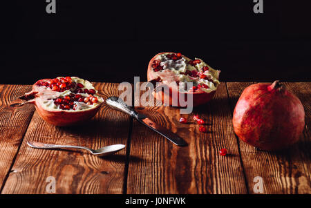 Appena aperto il Melograno frutta annata con un cucchiaio e un coltello Foto Stock