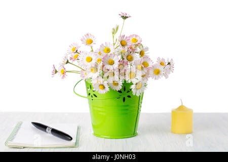 Daisy fiori in un vaso con notebook e una penna Foto Stock