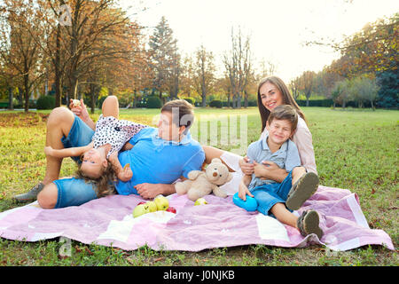 La famiglia felice avente un picnic nel parco della natura. Foto Stock