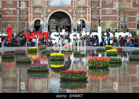 Fiori in stagno davanti al Rijksmuseum, con molti turisti su e intorno alla Iamsterdam segno. Foto Stock