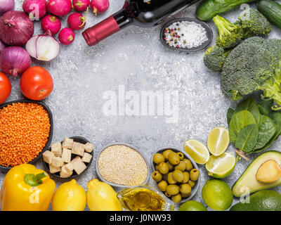 Cibo colorato sfondo. Gli ingredienti alimentari con copia spazio. Cereali, Ortaggi e bottiglia di vino sul cemento grigio Sfondo. Foto Stock