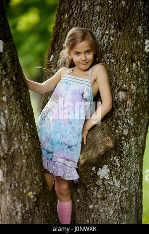 La ragazza si arrampica grande albero in posizione di parcheggio Foto Stock