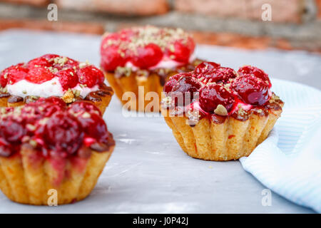 Torte fatte in casa di sweet berry cesti con ciliegie e lamponi sullo sfondo di una parete di pelatura. Foto Stock