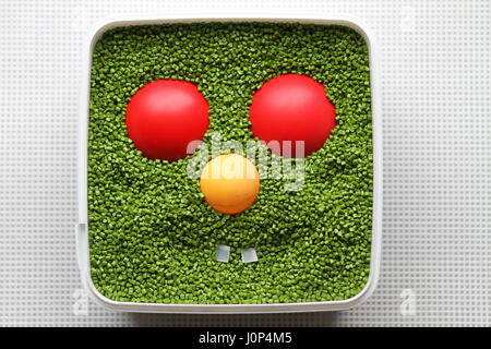 Il design creativo. Dell'opera dell'autore. Sorriso. Faccia di plastica. Emoticon per uso in giochi per computer e web design. Emoticon verde con rosso e giallo occhi naso. Foto Stock