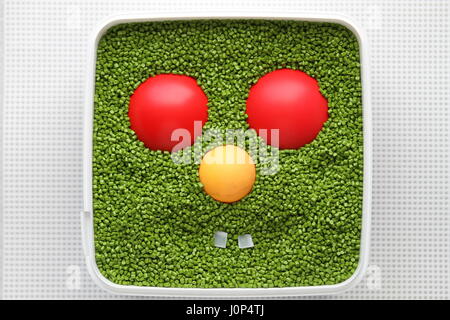 Il design creativo. Dell'opera dell'autore. Sorriso. Faccia di plastica. Emoticon per uso in giochi per computer e web design. Emoticon verde con rosso e giallo occhi naso. Foto Stock