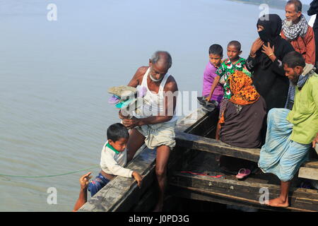 Un uomo aiuta un bambino per entrare in un motore-run barca al canale Moktaria in Hatia's Nijhum Dwip. Noakhali, Bangladesh Foto Stock