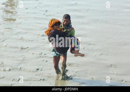 Un uomo aiuta una donna per entrare in un motore-run barca al canale Moktaria in Hatia's Nijhum Dwip. Noakhali, Bangladesh Foto Stock