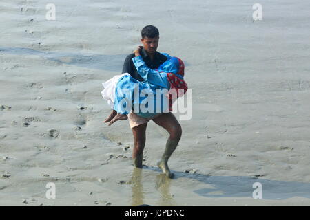 Un uomo aiuta una donna per entrare in un motore-run barca al canale Moktaria in Hatia's Nijhum Dwip. Noakhali, Bangladesh Foto Stock