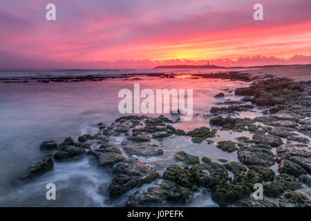 Ultime luci a Capo Trafalgar con le onde che si infrangono sulle rocce e faro di Trafalgar in background, Cadiz, Spagna Foto Stock