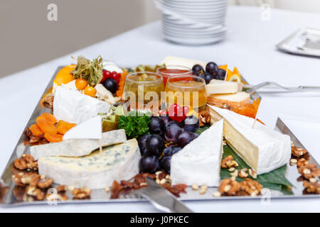 Raccolta di vari tipi di deliziosi piatti di formaggio, uva e i dadi su una di colore grigio chiaro nella tabella Foto Stock