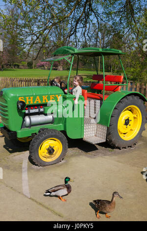 Due ragazze riprodotto nell'area di gioco con una riproduzione di un modello in scala del trattore a Glebe Farm, Astbury, Congleton, Cheshire. Regno Unito. (87) Foto Stock