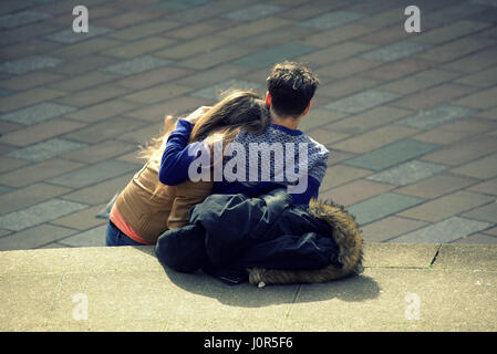 Coppia giovane cuddling insieme ragazza ragazzo seduto sul Glasgow concert hall passi in corrispondenza della giunzione di Buchanan Street e Sauchiehall Street Foto Stock