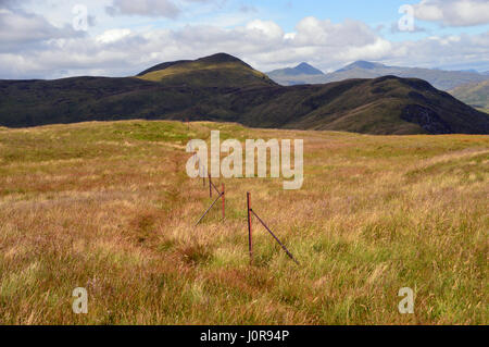 Una linea di Rusty Fence messaggi su Stuc Dhubh appena a sud della montagna scozzese Corbett Bennane nel Parco Nazionale Trossachs, Highlands scozzesi. Foto Stock