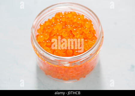 Il caviale di trota in vaso su sfondo blu Foto Stock