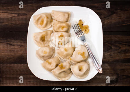 Tradizionale polacco gnocchi di patate, 'pierogi ruskie' sulla piastra bianca sul tavolo di legno. Foto Stock
