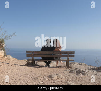 Giovane seduto su un banco di fronte all'oceano Foto Stock