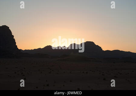 Un tramonto sul contorno scuro di una montagna nel Wadi Rum desert, la famosa Valle della Luna guardando come il pianeta di Marte Foto Stock