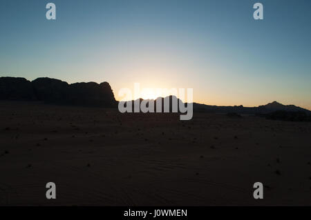 Un tramonto sul contorno scuro di una montagna nel Wadi Rum desert, la famosa Valle della Luna guardando come il pianeta di Marte Foto Stock