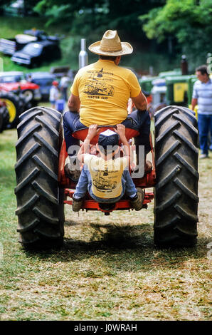 Ragazzo di agganciare una corsa sul retro di un antico trattore cavalcando attraverso il Cornish in fiera della Cornovaglia, New Hampshire, Stati Uniti. Foto Stock