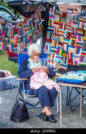 Un bianco-pelose old Lady maglieria un maglione rosa in un mercato all'aperto negli Stati Uniti. Foto Stock