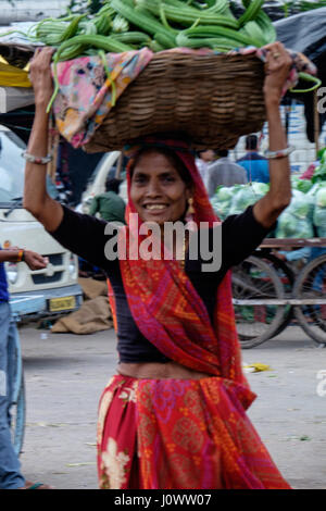 Signora nel mercato asiatico, India, con cesto di merci sulla testa Foto Stock