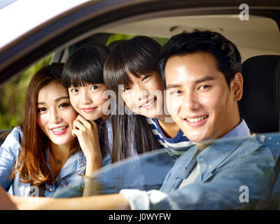 Felice famiglia asiatica con due bambini che viaggiano in auto Foto Stock