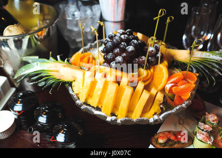 Piatto con frutta tagliata su spiedini spolverati con zucchero a velo. Vista superiore Foto Stock